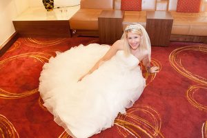 Bride sat on lush red carpet in her wedding dress