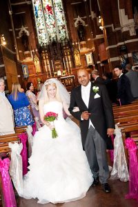 Newly married couple exiting St Michael and All Angels Church in Essex after their wedding ceremony