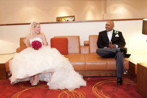 Bride and groom sat on a leather sofa in the Marriott Hotel in Waltham Abbey, Essex and smiling at one another