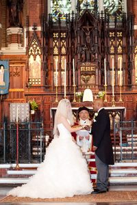 Bride and groom exchange vows in front of large organ inside St Michael and All Angels Church, Essex