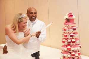 Bride and groom holding knife before cutting wedding cake the Marriott Hotel in Waltham Abbey, Essex